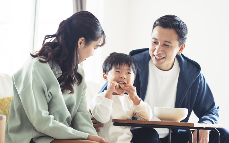 おやつを頬張る子供と両親