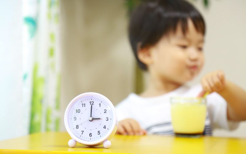 おやつの時間を指す時計と子供