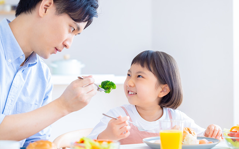 ブロッコリーを子どもに食べさせようとする父親