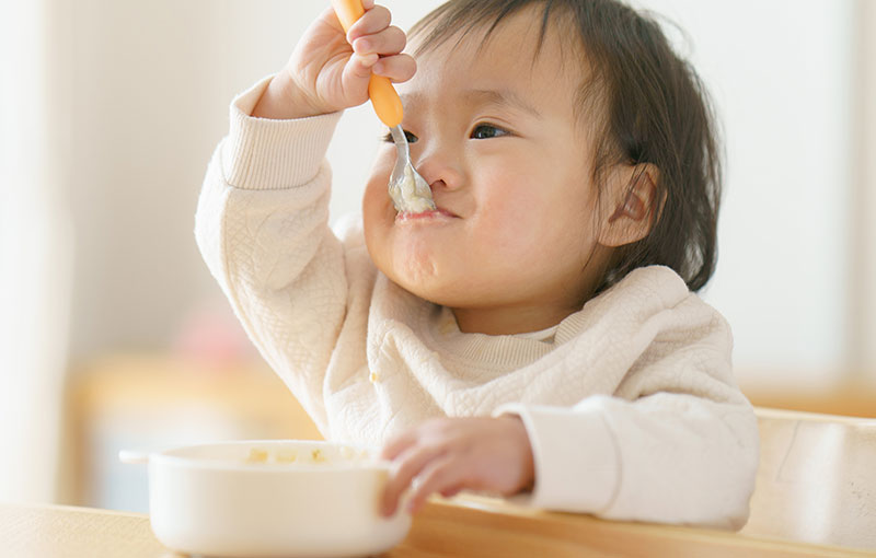 スプーンでご飯を食べる赤ちゃん